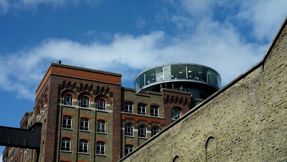 Historisch bakstenen gebouw met een moderne glazen koepel op het dak tegen een blauwe lucht met wolken. De koepel, mogelijk een observatiedek of restaurant, heeft grote ramen bovenop dit Ierse architectonische juweeltje en is een opvallende bezienswaardigheid voor degenen die op een rondreis Ierland op zoek zijn naar unieke contrasten. | Echt Ierland Vakanties