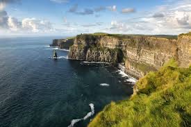 Ontdek de adembenemende Cliffs of Moher in Ierland, waar ruige kliffen dramatisch oprijzen uit de Atlantische Oceaan. Groen gras bedekt de top, met kalme zeeën eronder. Terwijl het zonlicht over dit betoverende landschap danst, is het een hoogtepunt van elke vakantie in Ierland. | Echt Ierland Vakanties